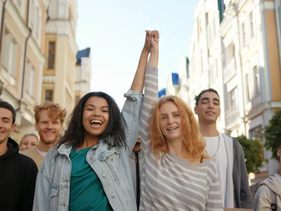 two women holding hands in air at front of a group outdoors