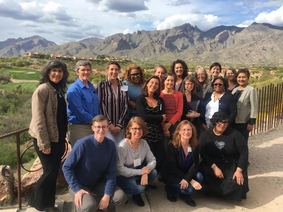 group standing on dirt path with mountains in the background